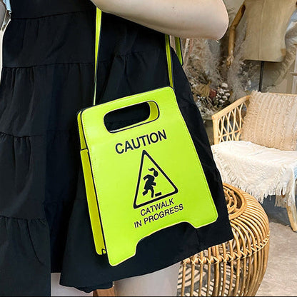 Person holding a bright yellow 'Caution: Catwalk in Progress' sign in a home setting.