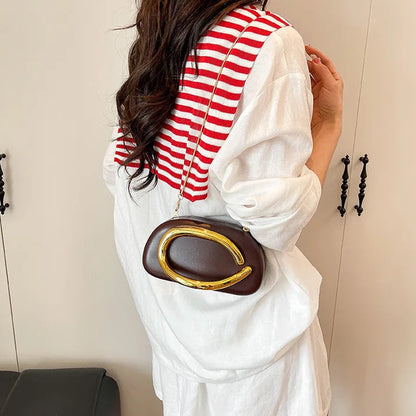 Person wearing a white outfit with a red and white striped top, holding a brown handbag with a gold emblem.