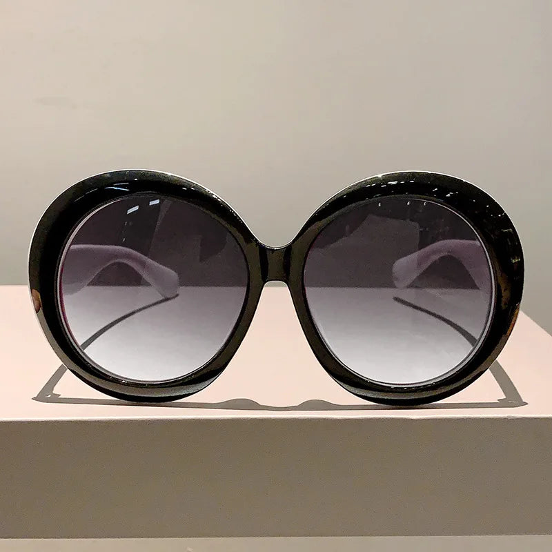 Black sunglasses with gradient lenses on a light gray surface