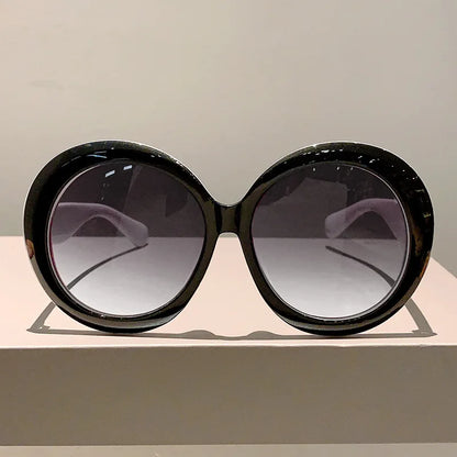 Black sunglasses with gradient lenses on a light gray surface