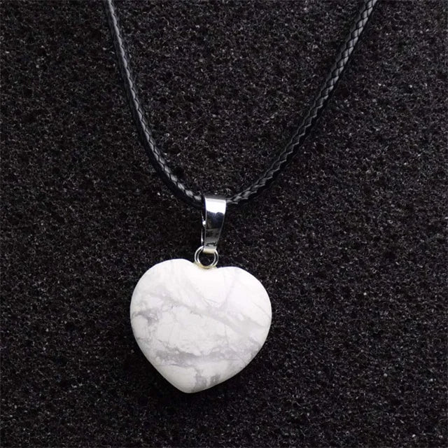Heart-shaped stone pendant on a black chain against a black background