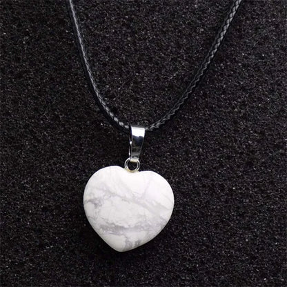 Heart-shaped stone pendant on a black chain against a black background