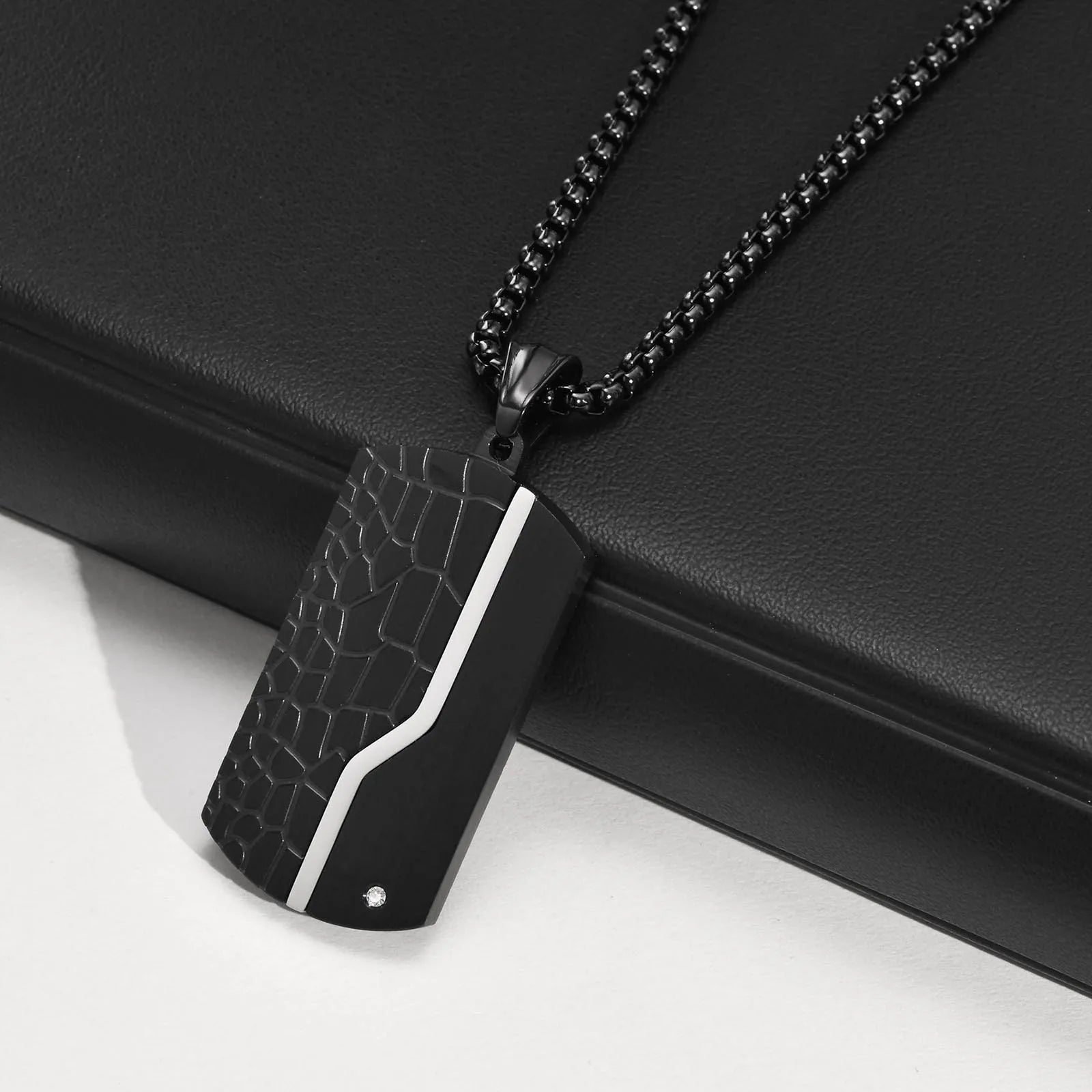 Black crocodile-patterned pendant on a chain against a black background