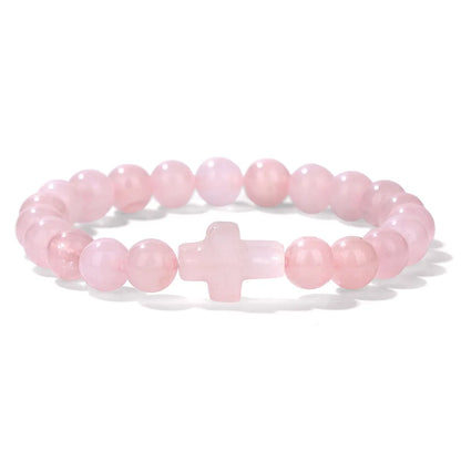 Pink beaded bracelet with a cross charm on a white background