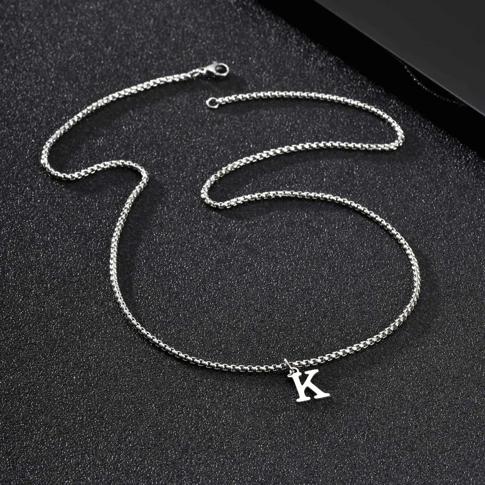 Silver chain necklace with a 'K' pendant on a black background