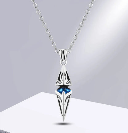 Silver pendant necklace with blue gemstone on a grey background.