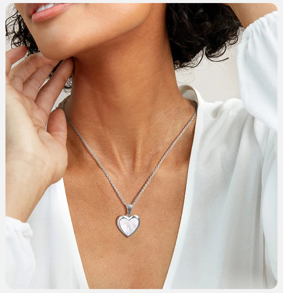 Woman wearing a silver heart-shaped pendant necklace.