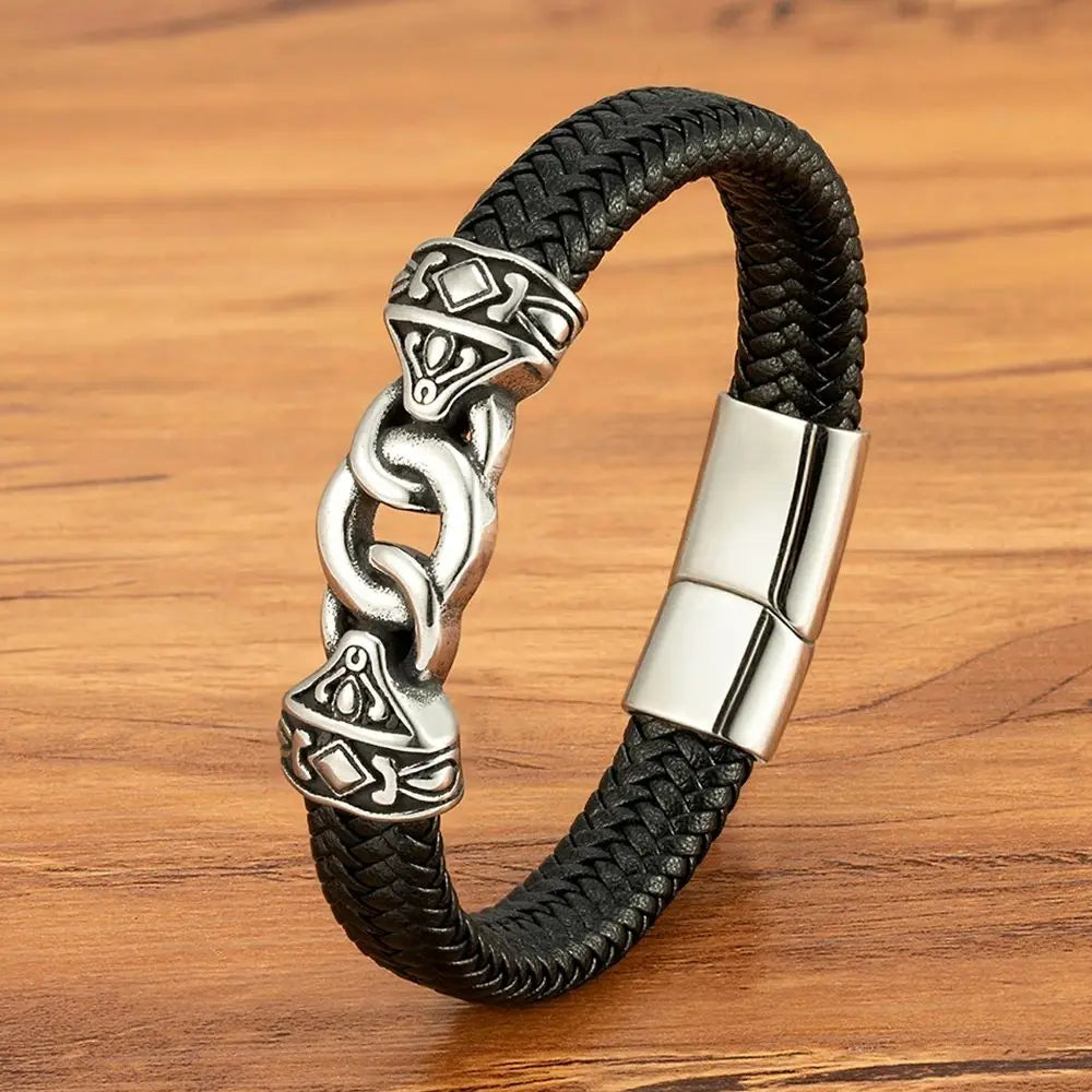 Black braided leather bracelet with silver Celtic knot design on a wooden surface