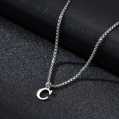 Silver necklace with a 'C' pendant on a black textured surface