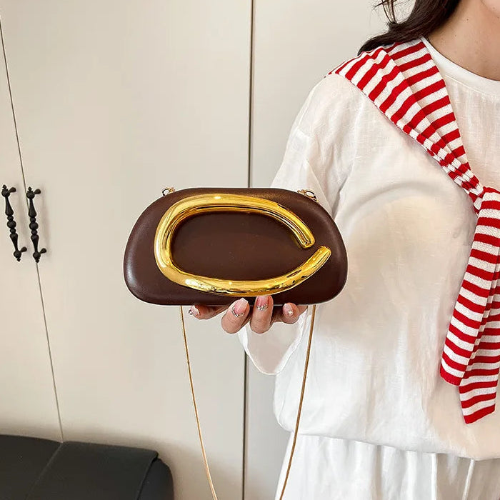 Person holding a brown clutch with gold handle against a neutral background