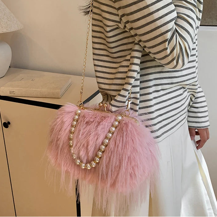 Person wearing a striped sweater and holding a pink fluffy handbag with beads.