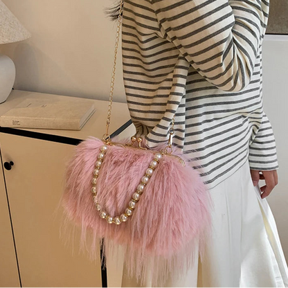 Person wearing a striped sweater and holding a pink fluffy handbag with beads.